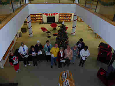 13 carollers standing in front of the Christmas tree 